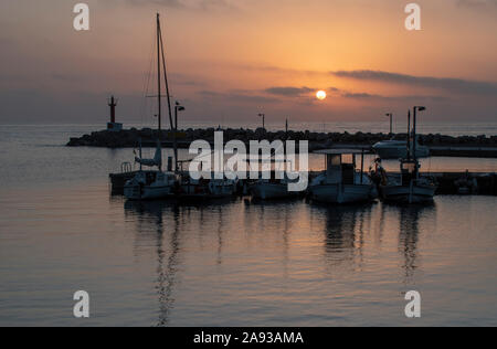 Cala Bona Marina Majorca Sunrise an array of golden colours and dramatic sky reflecting in the calm harbour water. Stock Photo