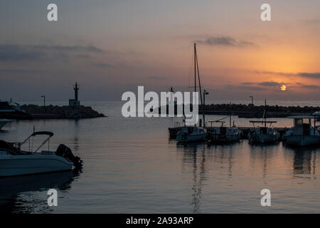 Cala Bona Marina Majorca Sunrise with golden colours and dramatic sky reflecting in the calm harbour water. Stock Photo