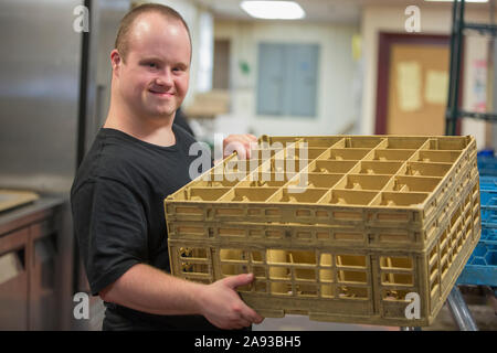 Waiter with Down Syndrome working in the kitchen of a restaurant Stock Photo