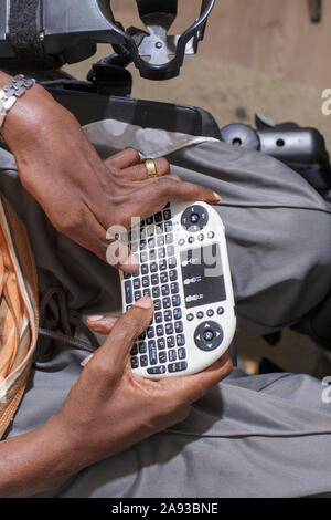 Man with Guillain-Barre Syndrome using his Bluetooth mini keyboard in his power chair Stock Photo