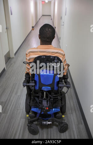 Man with Guillain-Barre Syndrome in the apartment hallway on his power chair Stock Photo