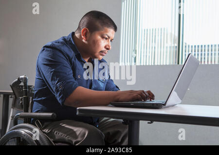 Hispanic man with Spinal Cord Injury working in an office Stock Photo