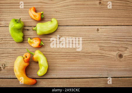 Flat lay Some ugly curved bent chilli peppers on white wooden background. Stock Photo