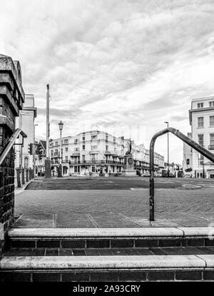 Steps leading up to  Marine Parade in Eastbourne.  A statue stands at the road junction with hotels in the background and a cloudy sky is overhead. Stock Photo