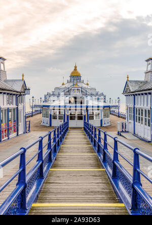 Eastbourne pier with a walkway to a cafe.  Shops with pagoda style domes are on wither side and a cloudy sky is above. Stock Photo