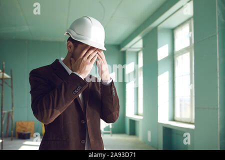 Foreman builder covered his face the problem of stress in the work on the construction site Stock Photo