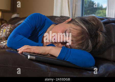 Woman with visual impairment lying down with her computer on sofa in living room Stock Photo