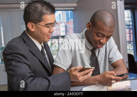 Two men with Autism looking at their cell phones in an office Stock Photo