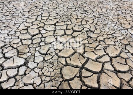 Pattern of cracked ground at the seashore. Brown, beige, light tan and grey colored background. Concept of global warming Stock Photo
