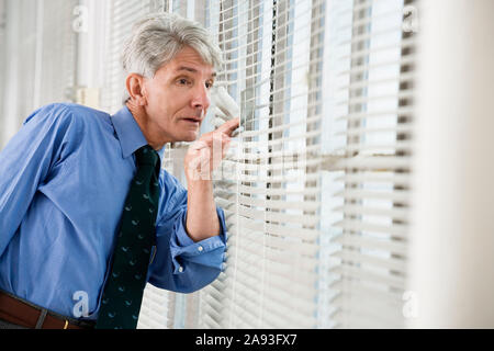 A business man looking out from his office window. Stock Photo