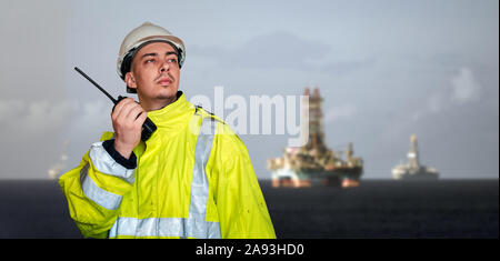 Ship supervisor engineer inspector stands at the dockside in a port. Wearing safety helmet, portablee radio and yellow vest. Cargo shipping industry. Stock Photo