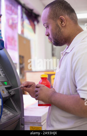 Man with Down Syndrome using a bank ATM Stock Photo