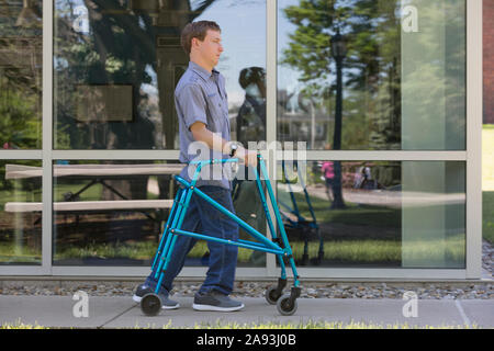 Young man with Cerebral Palsy using his walker to walk to work Stock Photo