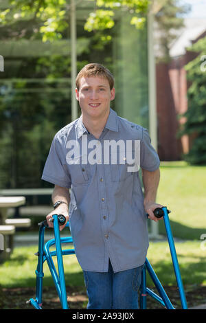 Young man with Cerebral Palsy using his walker to walk to work Stock Photo