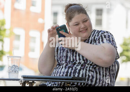 Woman with Visual Impairment sitting at a cafÃ© using her phone to communicate Stock Photo