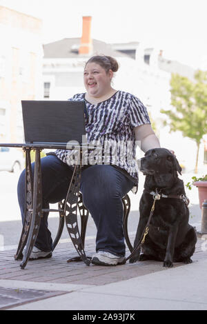 Woman with Visual Impairment sitting at a cafÃ© with her computer and service dog Stock Photo