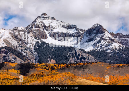 Scenic landscape with snow in the Sneffels Range in the San Juan Mountains above a grove of autumn Aspen trees near Telluride, Colorado, USA