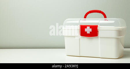 First Aid Kit. White box with a cross and a red clasp on a gray background. Stock Photo