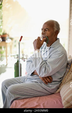 Unwell elderly man uses oxygen mask Stock Photo