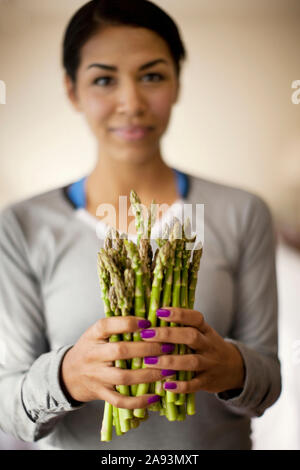 Portrait of a young woman holding a bunch of fresh asparagus Stock Photo