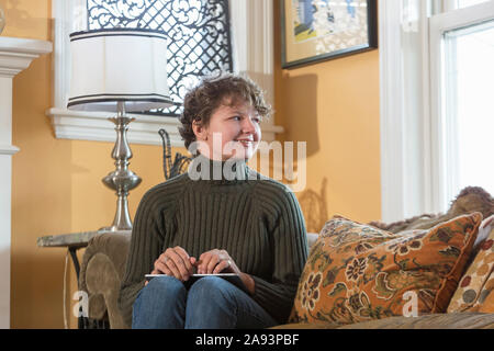 Woman with Sjogren-Larsson Syndrome resting on armchair Stock Photo