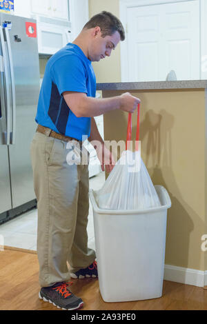 Man with Down Syndrome taking out garbage bag from dustbin Stock Photo