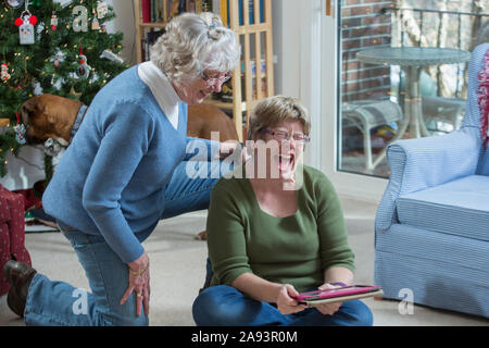 Woman with Autism using a digital tablet with her mother Stock Photo