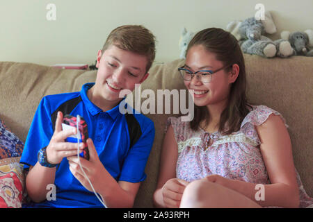 Teenage girl who has Learning Disability looking at phone with her brother Stock Photo