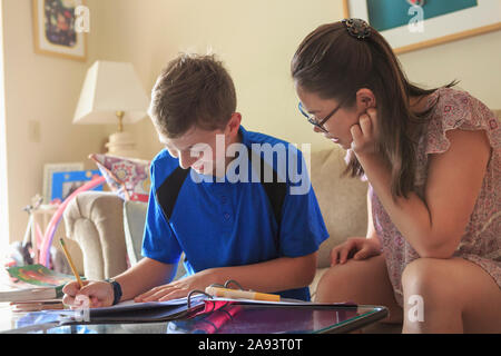 Teenage girl who has Learning Disability studying with her brother Stock Photo