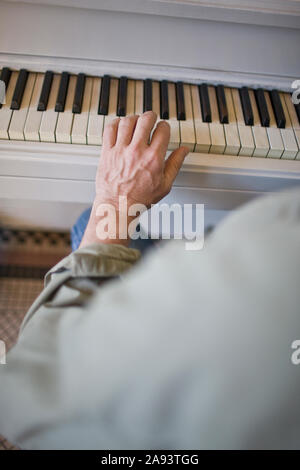 Man's hand playing keys on a piano. Stock Photo