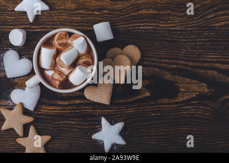 Hot chocolate, cocoa with marshmallows, star shape and heart shape Christmas cookies on the festive rustic wooden table, top view Stock Photo