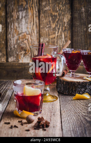 Glasses of Christmas mulled red wine with spices and oranges slices on rustic wooden table. Traditional autumn and winter hot drinks Stock Photo