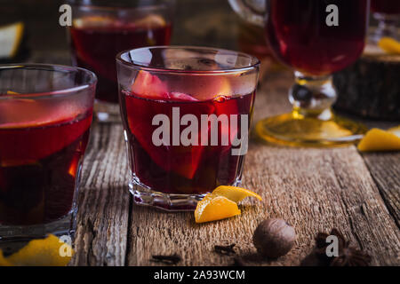 Glasses of Christmas mulled red wine with spices and oranges slices on rustic wooden table. Traditional autumn and winter hot drinks Stock Photo