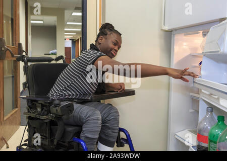Teen with Cerebral Palsy opening refrigerator in the kitchen Stock Photo
