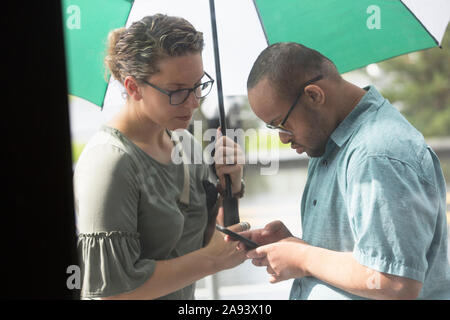 African American man who has Down Syndrome looking at his phone with his friend Stock Photo