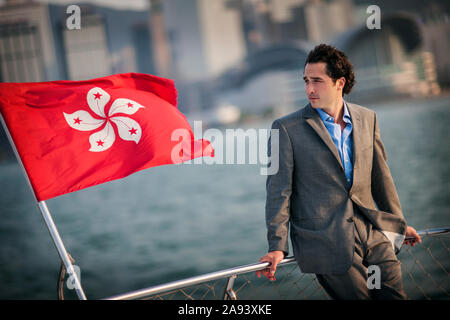 Mid adult man leaning against a boat railing looking thoughtful. Stock Photo