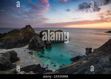 A beautiful landscape image of the National Trust's Kynance Cove in Cornwall, UK at sunset with colourful sky and turquoise ocean in a picturesque tra Stock Photo