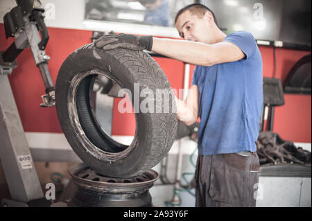 Car master mechanic vulcanizer repairing tire on automatic rubber repair vulcanizer machine in auto vulcanizing and vehicle service workshop Stock Photo