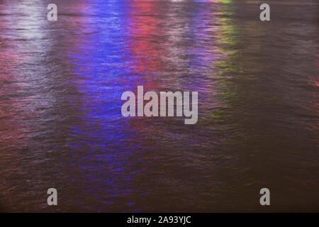 Multi-colored city lights reflecting on water in a harbor at night. Stock Photo