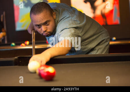 Man with Down Syndrome playing pool Stock Photo