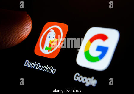 DuckDuckGo app on a smartphone screen next to Google search app and a finger touching it. Selective focus. Stock Photo
