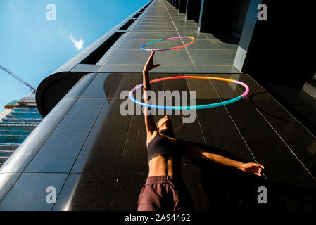 Low angle view of mixed race woman performing Hula Hoop dance in city Stock Photo