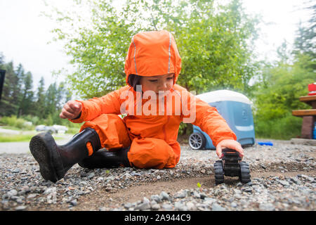 Toddler boy driving toy truck on dirt track. Stock Photo