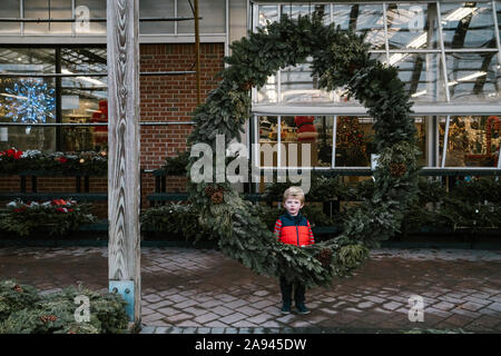 A little boy stands behind a huge wreath. Stock Photo