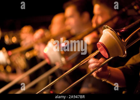 Jazz Big Band trombone section with cup mutes. Shallow focus on the foreground trombonist with the rest of the section falling into background blur. Stock Photo