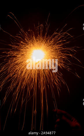 sparkler in hand on a black background. Long bright sparks fly in different directions. Long exposure Stock Photo