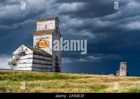 Weathered grain elevator and storm on the prairies; Saskatchewan, Canada Stock Photo