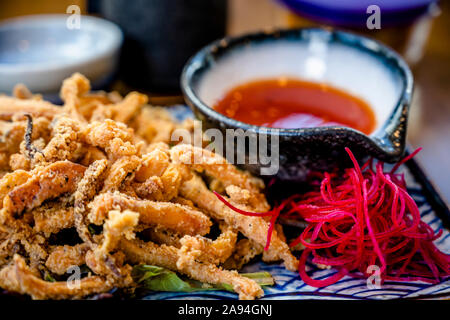 Plates with various kinds of expertly cooked fried squid with spices and hot sauces are displayed on dining table to enjoy delicious and dietary natur Stock Photo