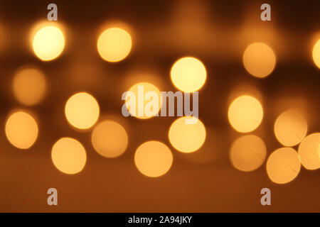A collection of bright, shining, circular lights against a soft golden background. Stock Photo