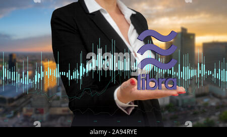 businesswoman presenting the Libra cryptocurrency logo on the background of modern architecture Stock Photo